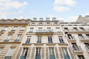 A multi-story building with classic architectural features, including ornate balconies and shutters. - Comfortable Apartment 1BR/4P - Champs Élysées (Paris)