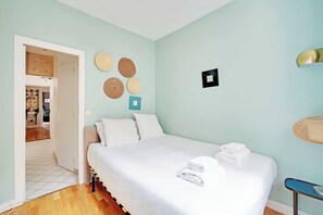 A bedroom with a bed, a door leading to a hallway, and a wall with decorative items. - Comfortable Apartment 1BR/4P - Champs Élysées (Paris)