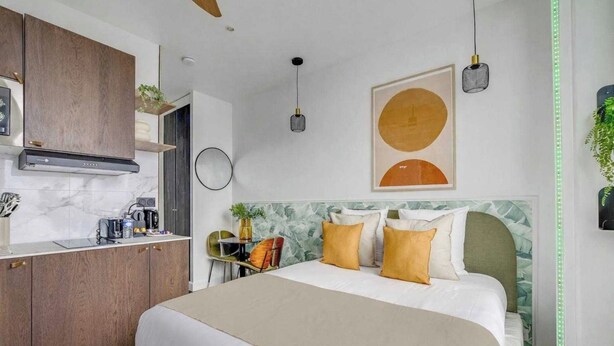Een moderne hotelkamer met een bed, een bureau en een kitchenette.