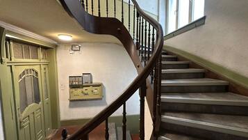 Un escalier avec une rampe en bois et une porte verte dotée d’une fenêtre.