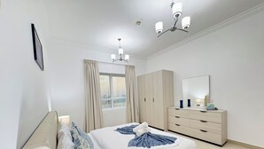 Ein modernes Hotelzimmer mit Bett, Schminktisch, Spiegel und einem Fenster mit Vorhängen.