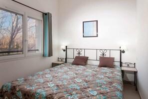 Ein Schlafzimmer mit einem Bett, zwei Nachttischen, einem Fenster und einem Wandbild.