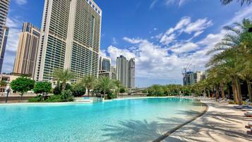 A pool with clear water, surrounded by palm trees and high-rise buildings.