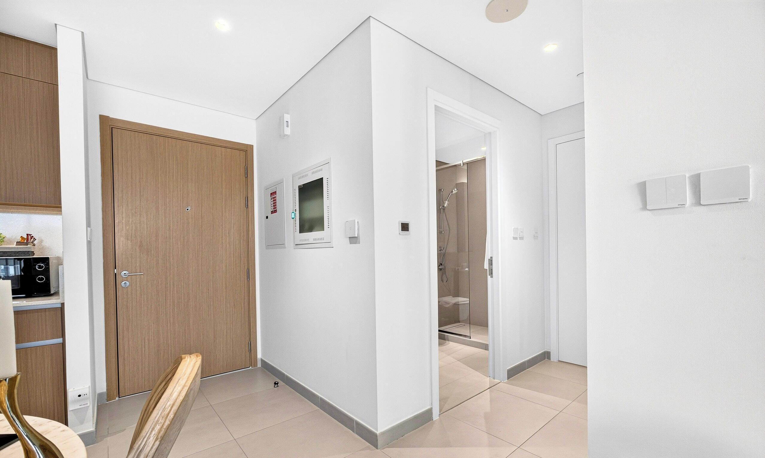 A modern kitchen with a microwave, a wooden door, and a white wall with a smoke detector.