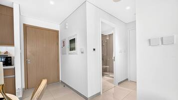 A modern kitchen with a microwave, a wooden door, and a white wall with a smoke detector.