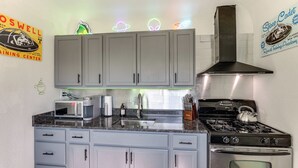 A kitchen with grey cabinets, a stainless steel stove, a microwave, and a sink. - Alien-Crash-Site-Themed Retreat in Roswell (Roswell)