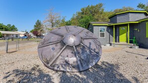A large metallic sculpture in a gravel area with a building in the background. - Alien-Crash-Site-Themed Retreat in Roswell (Roswell)