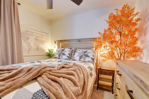 Ein Schlafzimmer mit einem Bett, einem hölzernen Kopfende, einer Weltkarte an der Wand, einer Pflanze und einer Kommode.