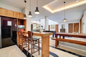Een moderne keuken met houten kastjes, een centraal eiland en hangende lampen.
