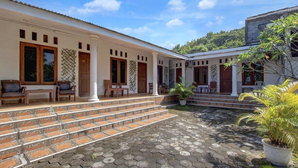 A building with a covered outdoor seating area, steps leading to a porch, and a potted plant. - Luxury Deluxe DBL Escape W/ Free WiFi and Parking (Yogyakarta)