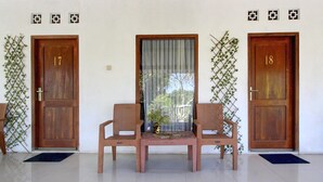 A room with two wooden doors, numbered 17 and 18, a window with a curtain, and two wicker chairs with a small table in between. - Luxury Deluxe DBL Escape W/ Free WiFi and Parking (Yogyakarta)