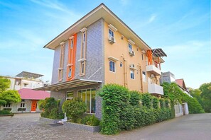 Un edificio de varios pisos con techo plano, ventanas grandes y entrada cubierta.