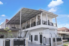 A two-story building with a covered balcony, air conditioning units, and a gated entrance. - Luxury Deluxe DBL Retreat W/ Free WiFi and Parking (Padang)