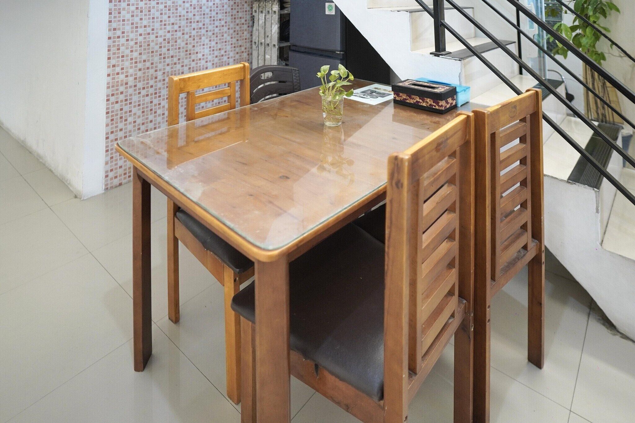 A wooden dining table with chairs, a small vase with plants, and a box on the table.
