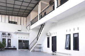 Un edificio de varios niveles con una escalera, unidades de aire acondicionado y un banco.