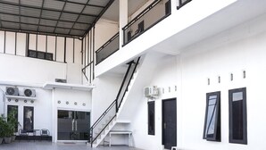 Un edificio de varios niveles con una escalera, unidades de aire acondicionado y un banco.