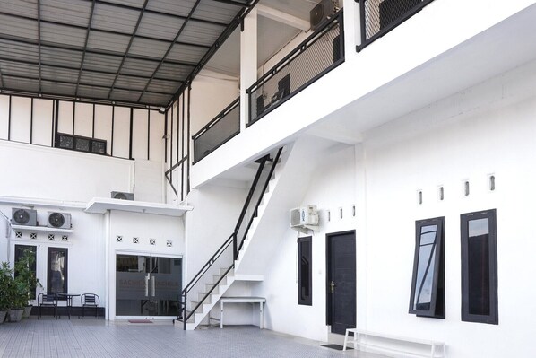 A multi-level building with a staircase, air conditioning units, and a bench.