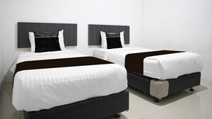 Dos camas con cabeceras, ropa de cama blanca y un detalle en negro.