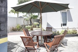 An outdoor patio with a round table, four wooden chairs, and a large umbrella. - Cozy Double Escape W/ Free WiFi and Parking (Padang)