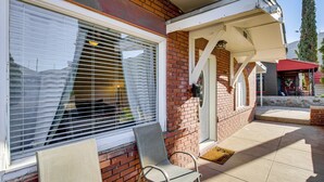 Een bakstenen gebouw met een overdekte patio, een deur en een raam met luiken.