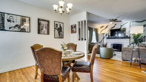 Een eetruimte met een ronde tafel en stoelen, een kroonluchter en ingelijste foto's aan de muur.