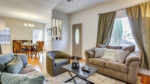 Een woonkamer met een bank, fauteuil, salontafel en een eethoek met stoelen en een tafel.