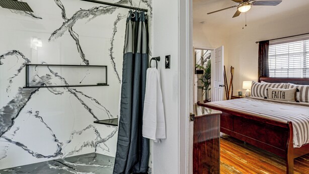 Een badkamer met een douche, een plafondventilator en een marmeren wand.