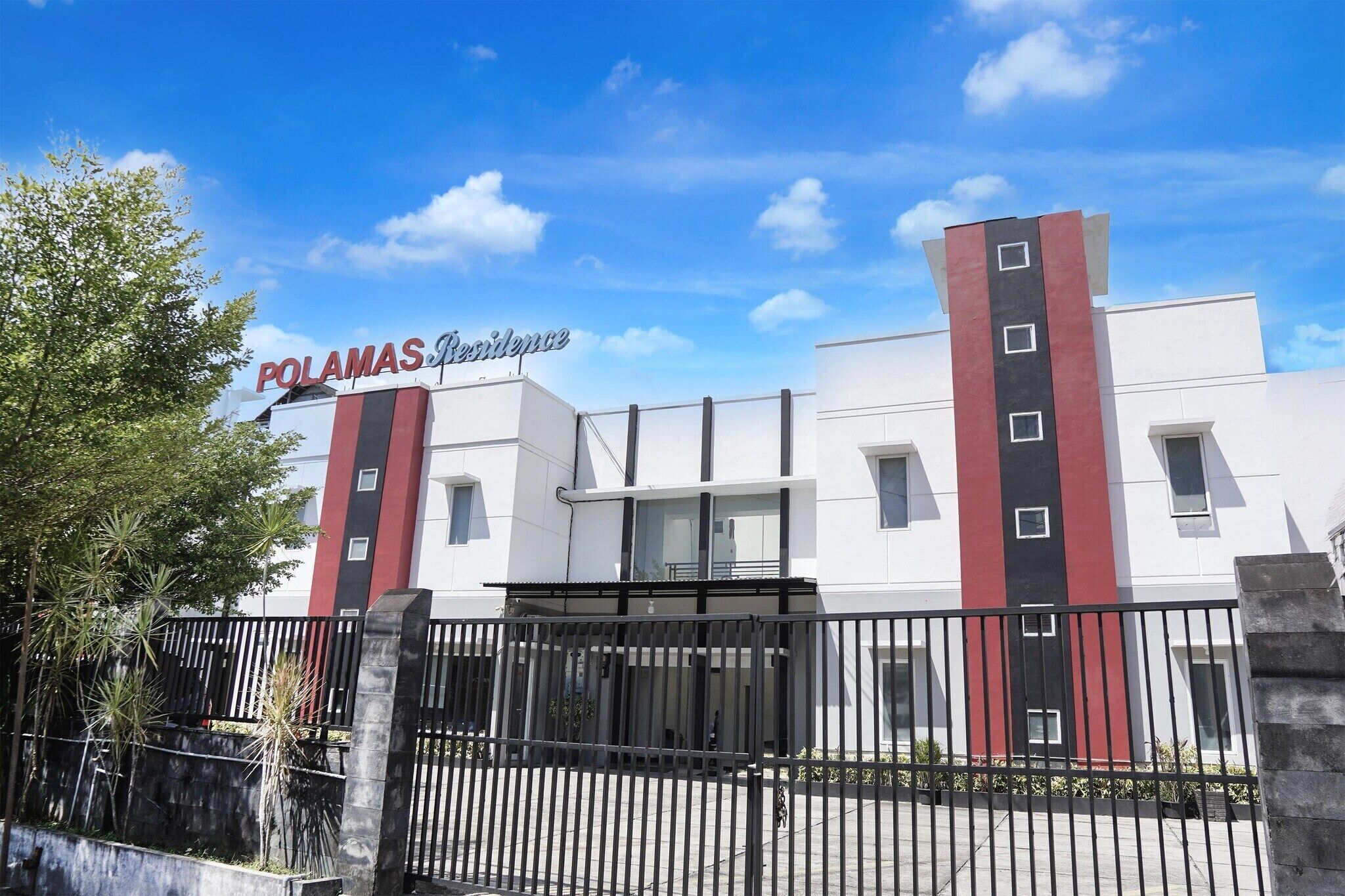 Edifici amb un rètol que diu 'POLAMAS Residence' i una entrada tancada per una reixa.