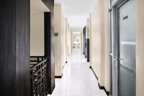 A corridor with a wooden railing, a door with a sign, and a tiled floor. - Family Friendly Suite W/Free WiFi Parking and Pool (Padang)