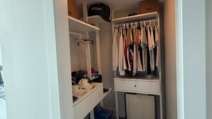 A walk-in closet with hanging clothes, shelves, and a desk with a chair. - Luxury Bridgeland 2BR/2BA – King Suite, Saddledome/City Views & Parking (Calgary)
