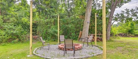 A circular seating area with a fire pit, surrounded by a gravel ring, and four wooden posts.