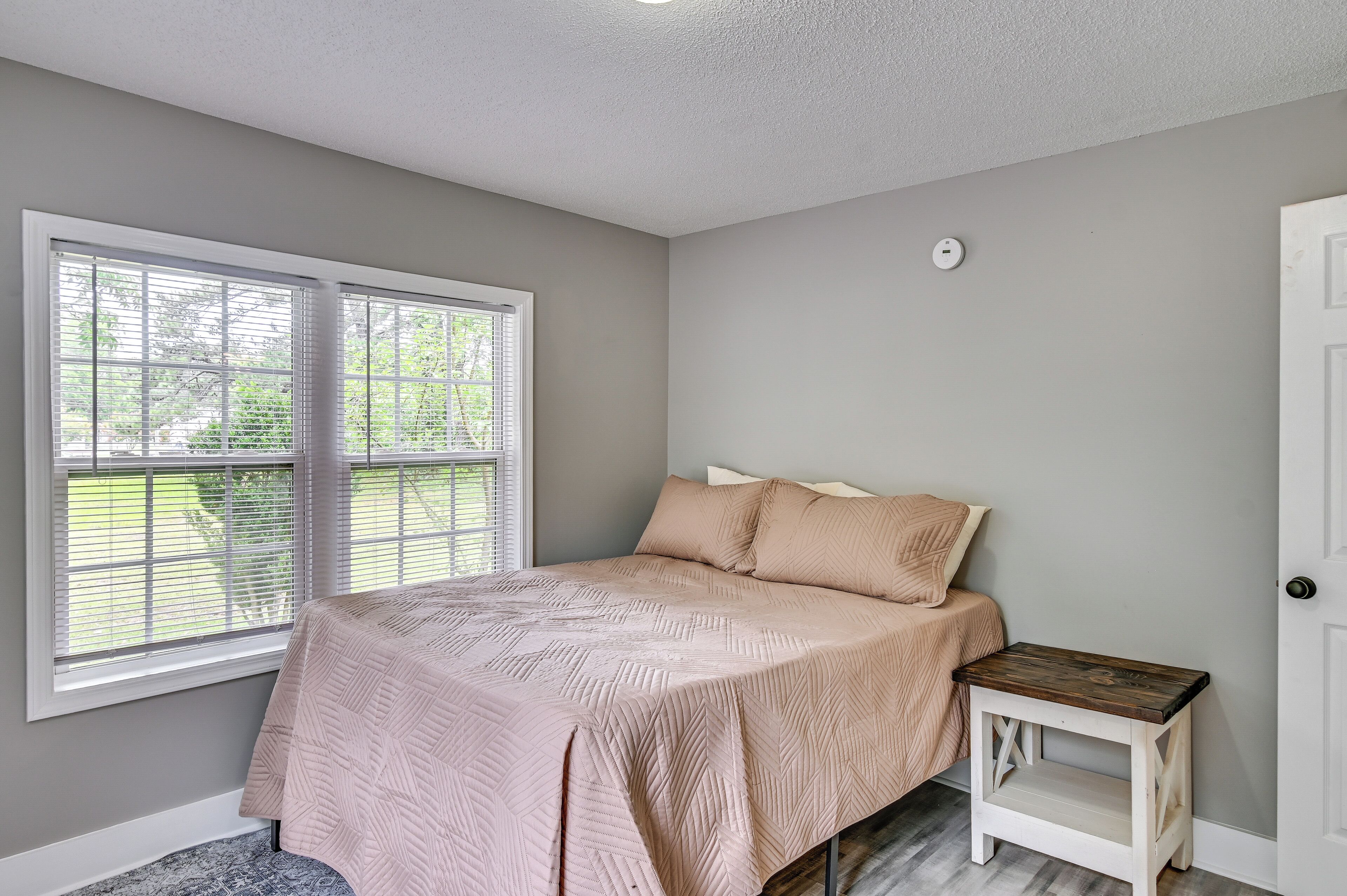 Une chambre à coucher avec un lit, une table de chevet, une fenêtre et une porte.