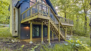 Een houten chalet met een balkon, een trap en een groot raam.