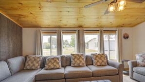 Ein modernes Wohnzimmer mit einem Ecksofa, einem kleinen Hocker und einem Deckenventilator.