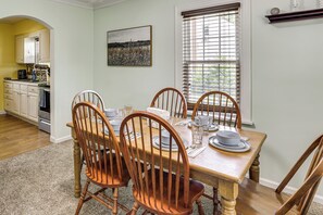 A dining area with a wooden table set for four, surrounded by wooden chairs.