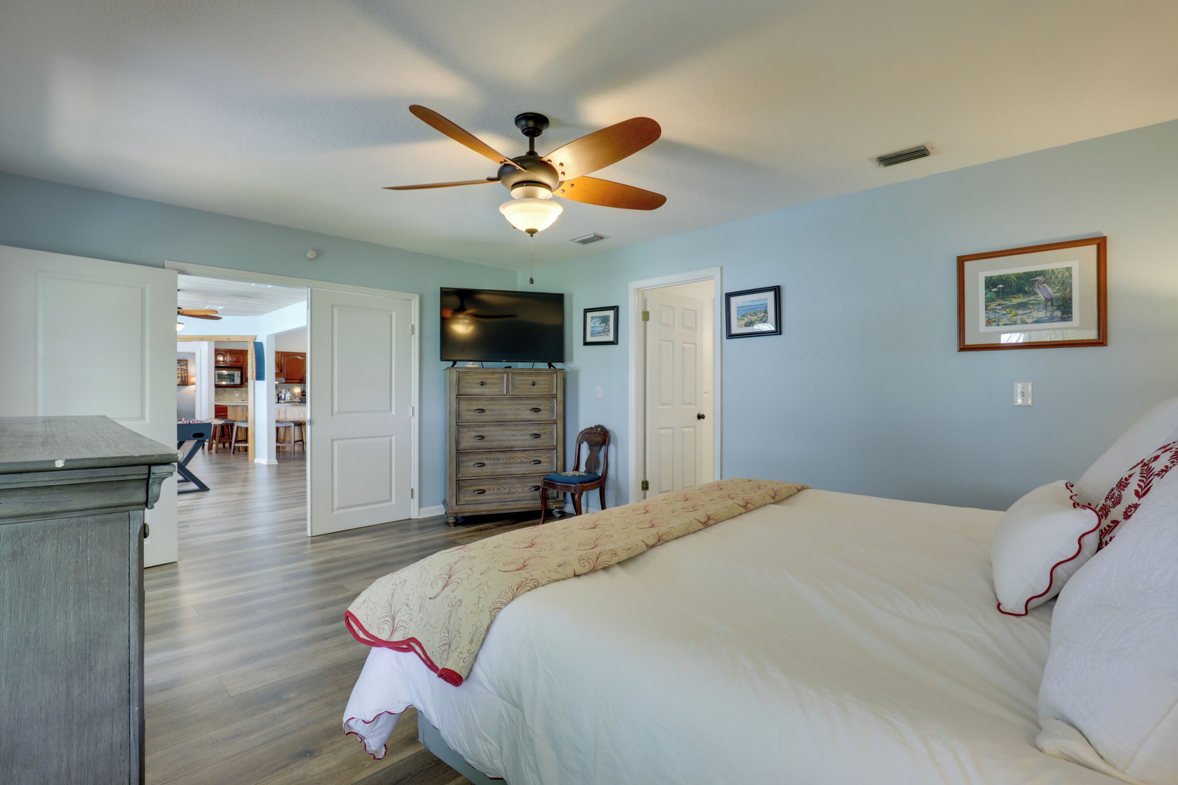 Une chambre à coucher comprenant un lit, un ventilateur de plafond, une commode et un téléviseur.