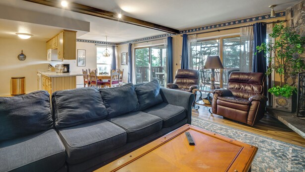 Ein Wohnzimmer mit einer Couch, einem Couchtisch, einem Ledersessel und einem Essbereich im Hintergrund.