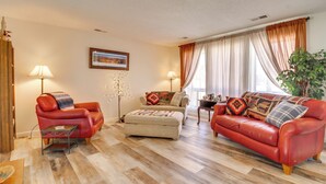 A living room with a red leather sofa, a beige armchair, a small wooden coffee table, and a floor lamp. - 2 Mi to Intel: Extended-Stay Retreat w/ Patio (Rio Rancho)