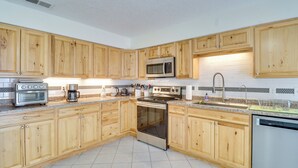 A kitchen with wooden cabinets, a microwave, a stove, a dishwasher, and a coffee maker. - 2 Mi to Intel: Extended-Stay Retreat w/ Patio (Rio Rancho)
