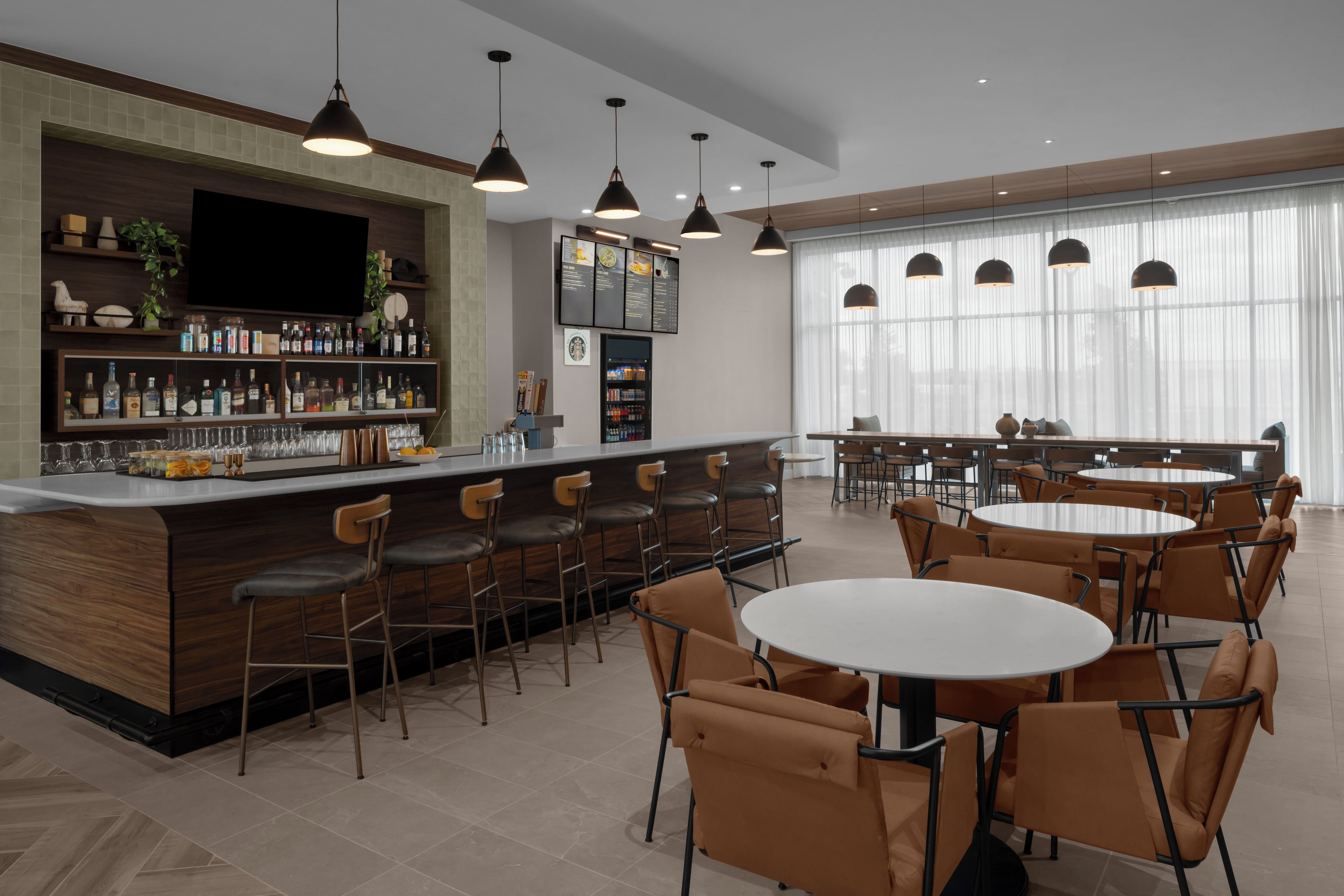 Zona de bar moderna con mostrador, taburetes y una pizarra con la carta.