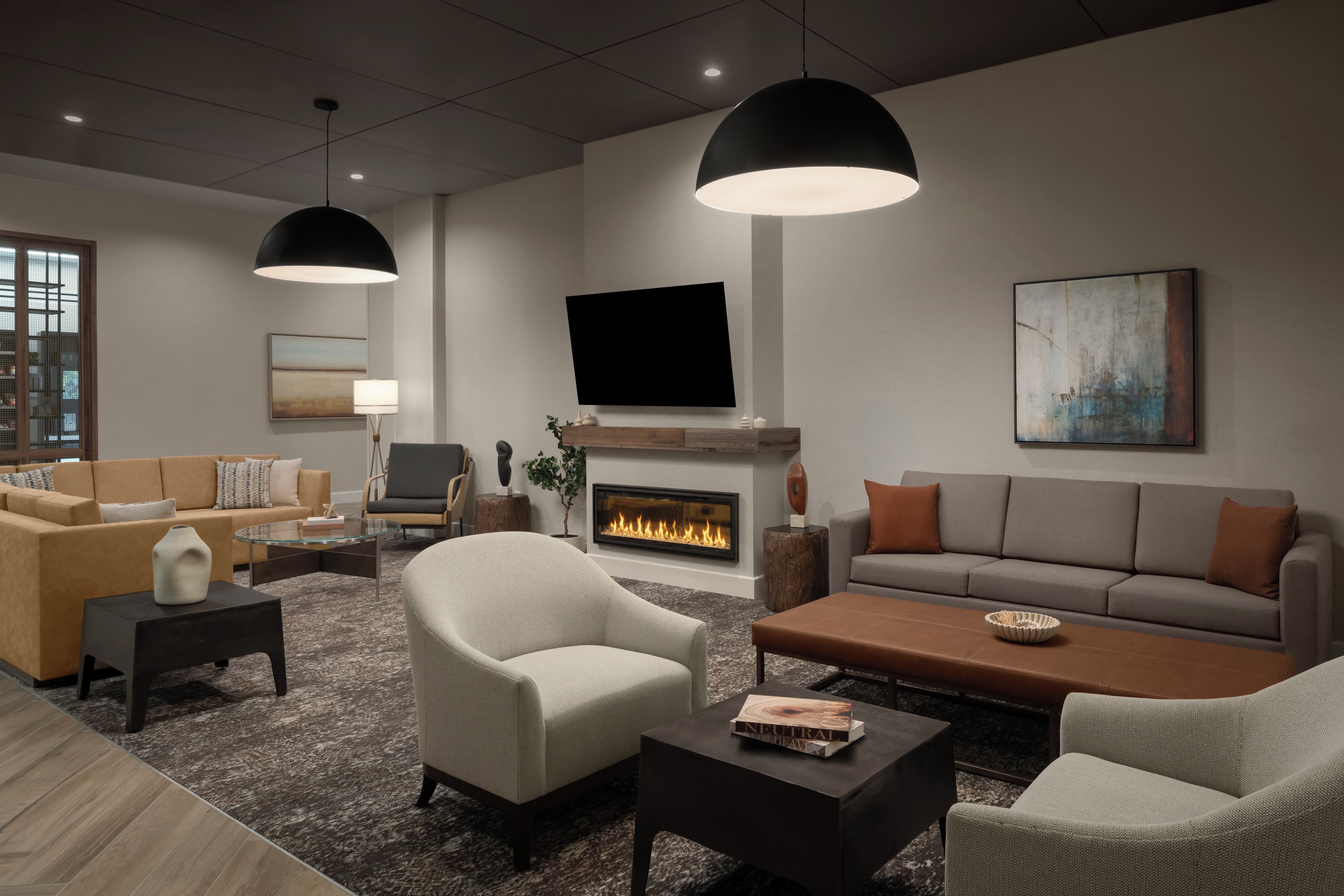 A modern living room with a fireplace, sofas, armchairs, and a flat-screen TV.