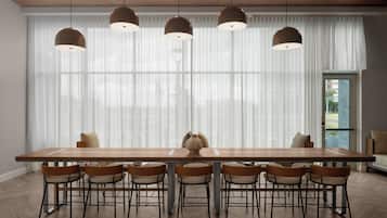 A modern dining area with a long wooden table, six chairs, and pendant lights.