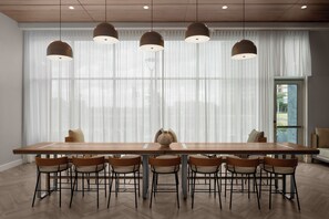 Un comedor moderno con una larga mesa de madera, seis sillas y lámparas colgantes.
