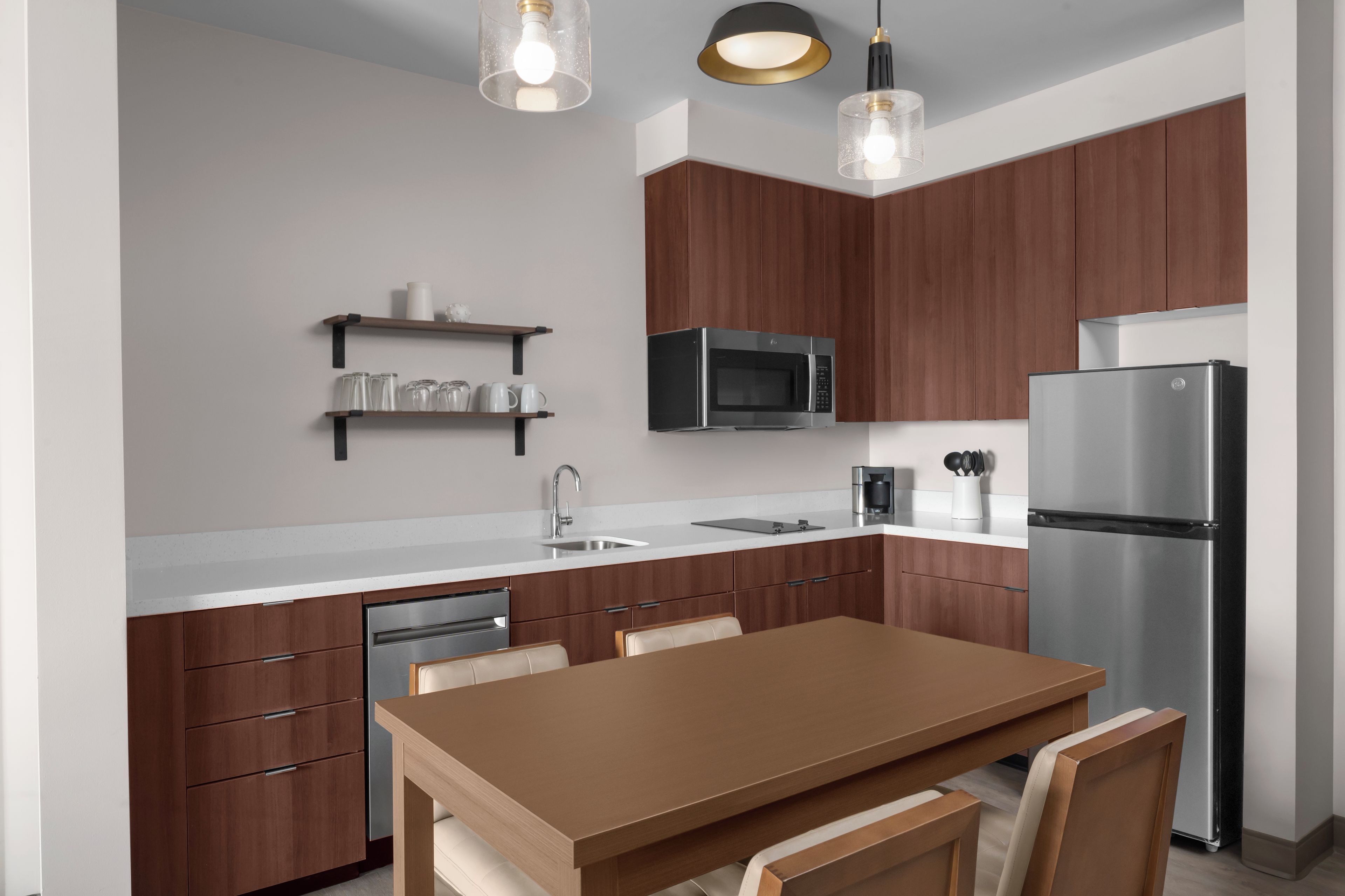 A modern kitchen with wooden cabinets, stainless steel appliances, and pendant lighting.