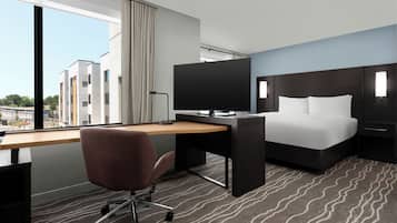 Een hotelkamer met een bed, bureau, stoel en televisie.