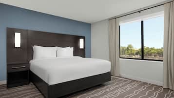 Een hotelkamer met een groot bed, een nachtkastje, een raam met gordijnen en uitzicht op de omgeving.