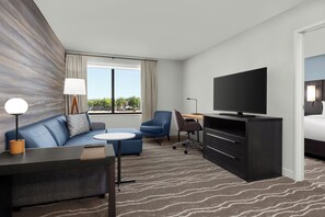 A modern hotel room with a sofa, a small table, a TV, a desk, and a bed. - Residence Inn by Marriott Irving Las Colinas (Irving)