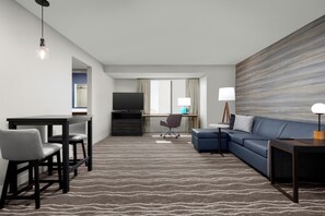 A modern hotel room with a flat-screen TV, a desk with a chair, a sofa, and a large abstract painting on the wall. - Residence Inn by Marriott Irving Las Colinas (Irving)