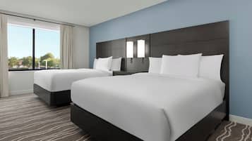 Een hotelkamer met twee bedden, een groot raam en uitzicht op de omgeving.