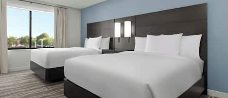 A hotel room with two beds, a large window, and a view of the outdoors.